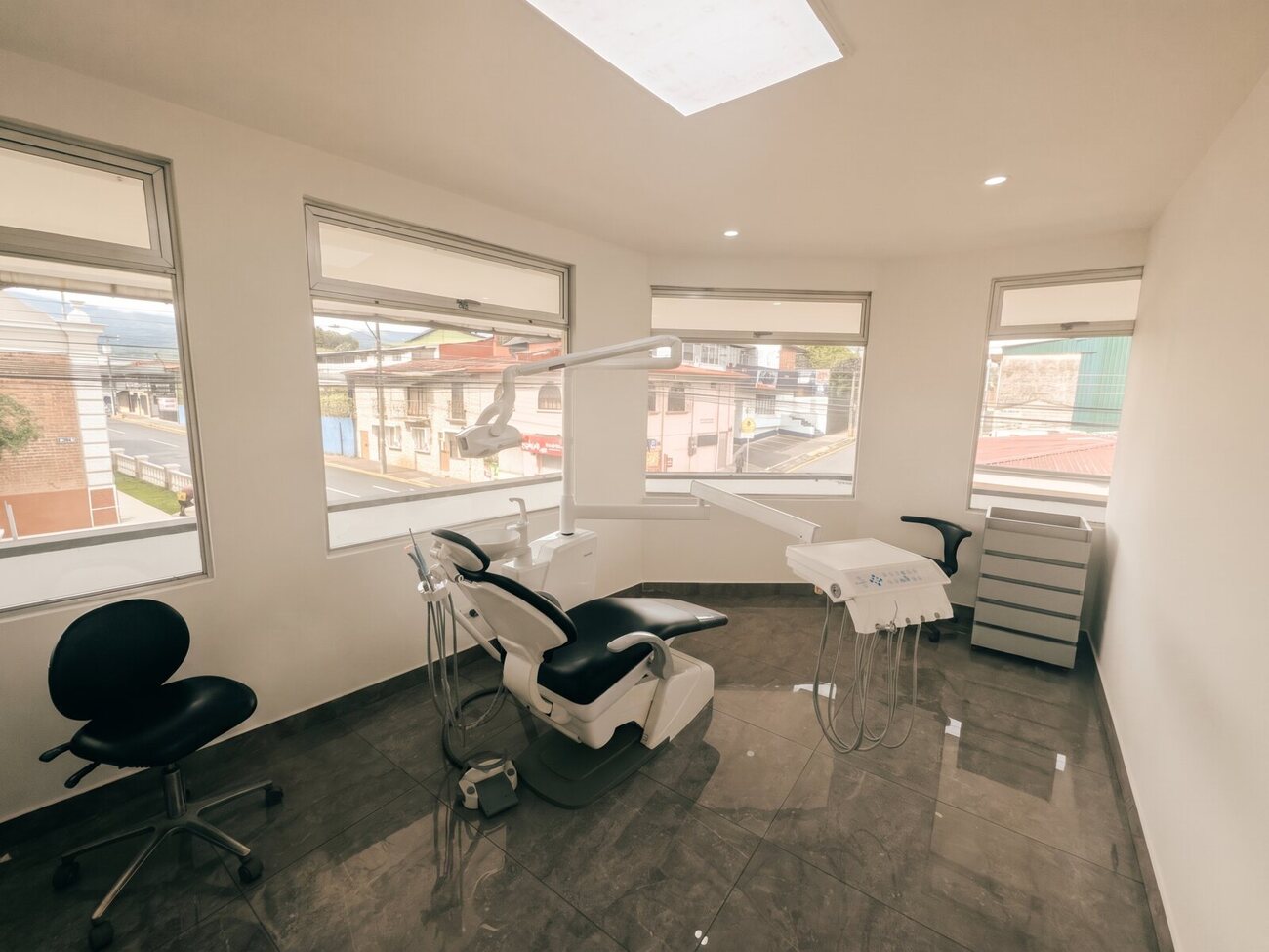 A treatment room at Galería Dental in Heredia, Costa Rica, with wraparound windows overlooking the street and mountains