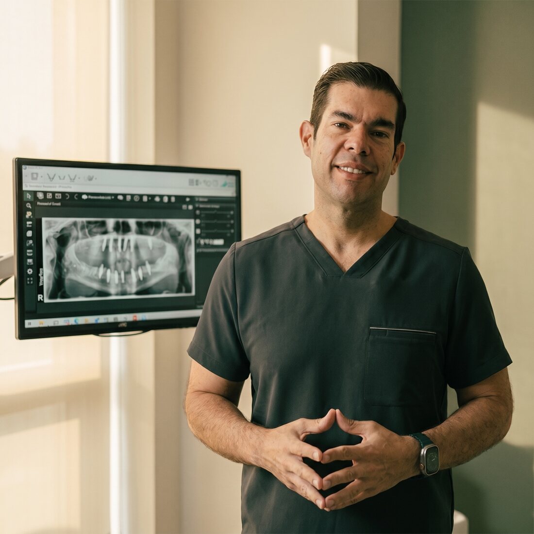 Dr. Carlos Aguilar reviewing a patient's panoramic dental X-ray on a monitor at Galería Dental in Heredia